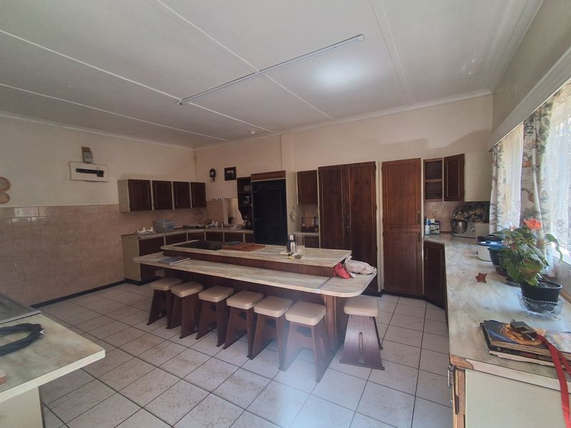 Spacious kitchen featuring extensive built-in cabinetry, a central island with integrated seating, and tiled flooring, offering a functional layout with potential for modern updates.