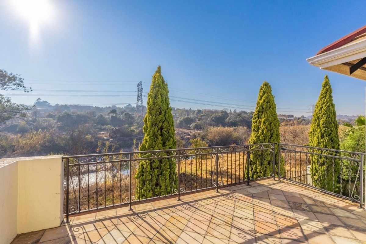 A spacious outdoor balcony featuring tiled flooring and a decorative wrought iron balustrade, offering expansive views of the surrounding landscape.