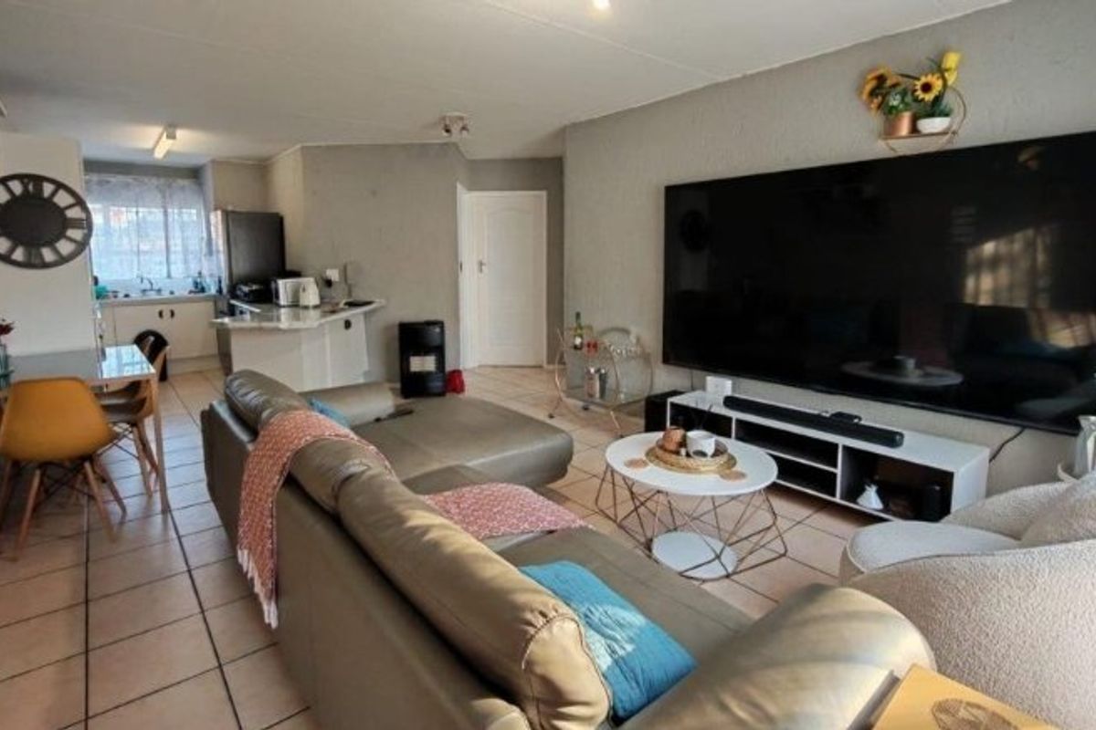 Open-plan living area featuring tiled flooring and a functional kitchen with a breakfast counter, creating a cohesive and practical living space.