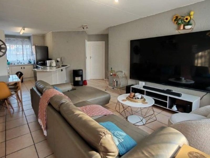 Open-plan living area featuring tiled flooring and a functional kitchen with a breakfast counter, creating a cohesive and practical living space.