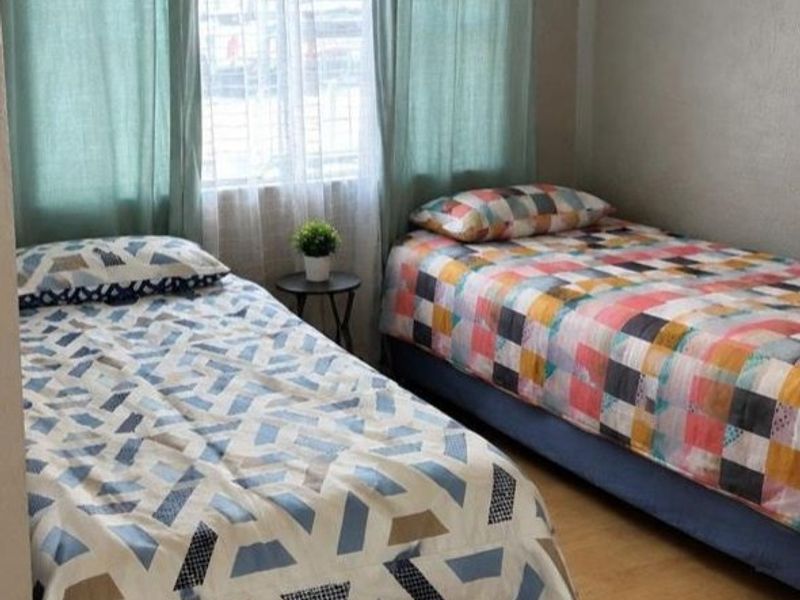 A functional bedroom featuring laminate flooring and security bars on the window, providing a practical space for residents.
