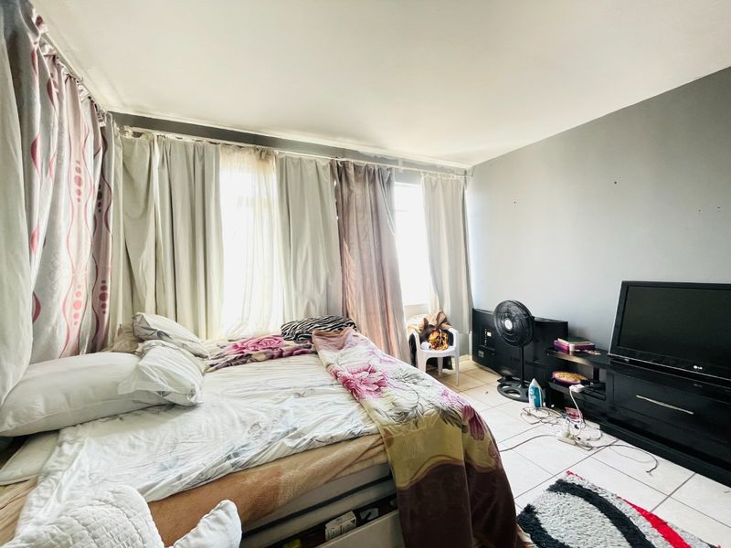 A bedroom featuring tiled flooring and large windows with curtain tracks, offering a functional space ready for personalization.
