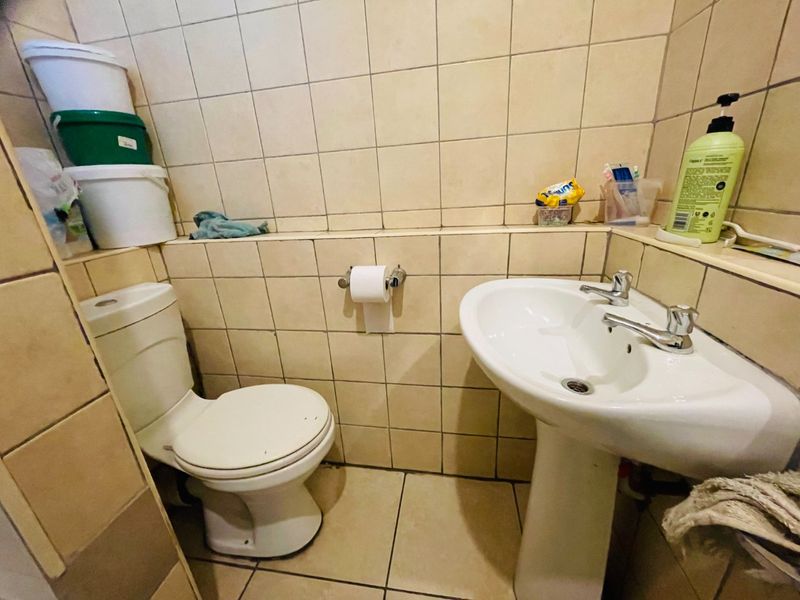 Compact bathroom featuring a pedestal basin and standard toilet with full-height ceramic wall tiling.