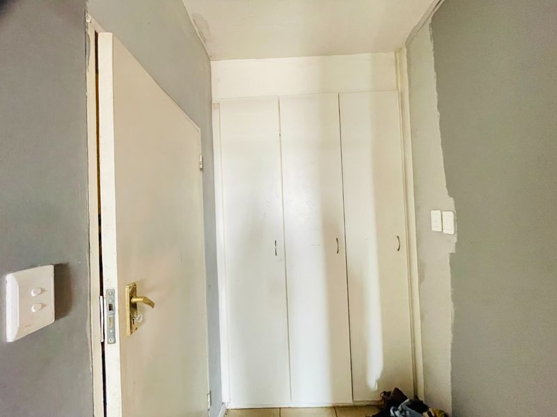 A hallway featuring built-in cupboards and unfinished wall paint, requiring cosmetic attention to complete the interior finish.
