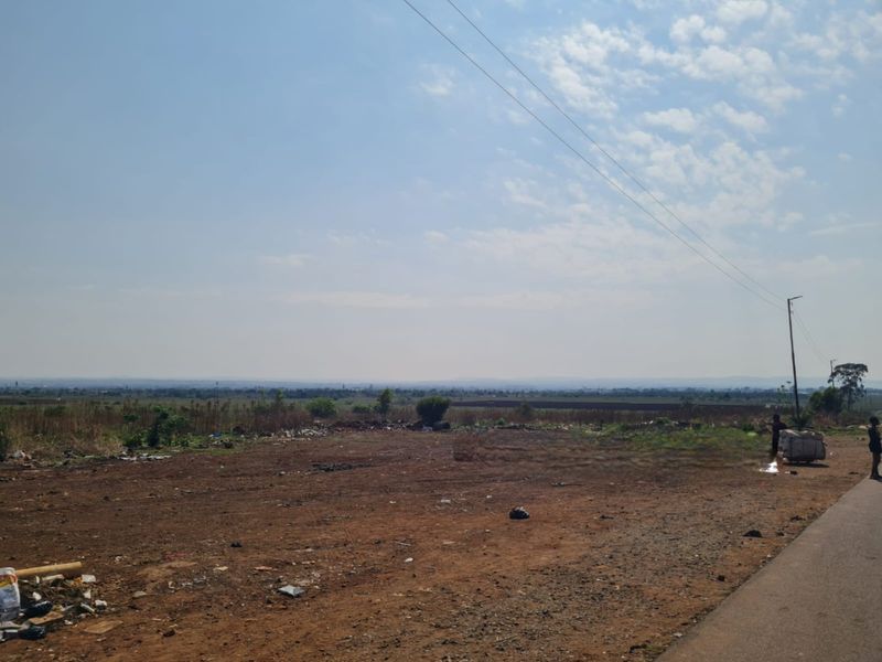 A vacant residential plot featuring open land, direct road access, and overhead power lines, offering a blank canvas for future development.