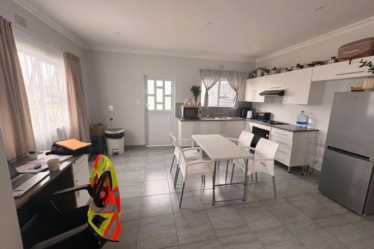 Open-plan kitchen and dining area featuring tiled flooring, modern white cabinetry, built-in oven and hob, and ample natural light.