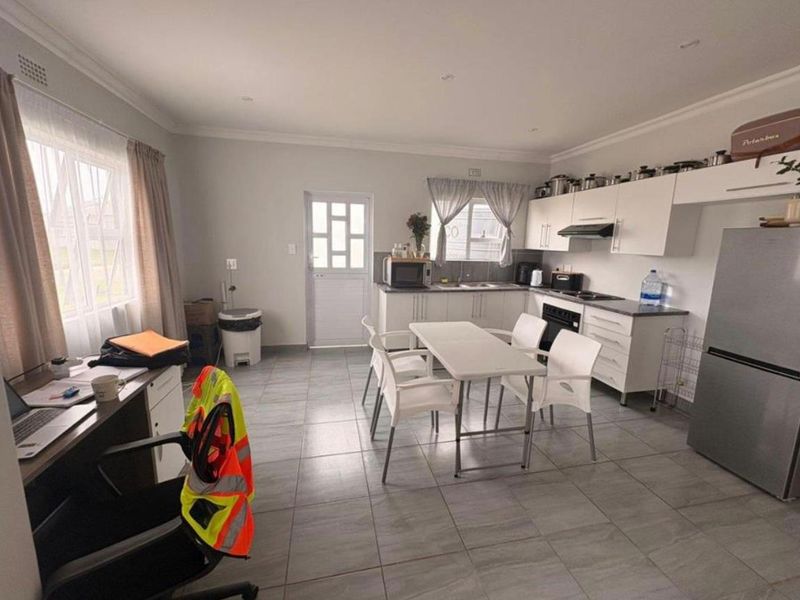 Open-plan kitchen and dining area featuring tiled flooring, modern white cabinetry, built-in oven and hob, and ample natural light.