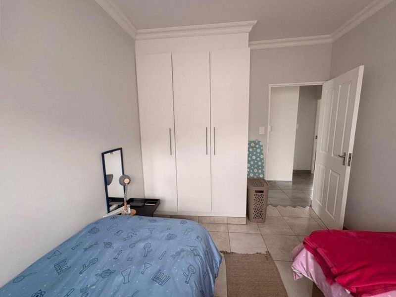 A functional bedroom featuring built-in cupboards, neutral wall finishes, and tiled flooring, providing a clean and practical living space.