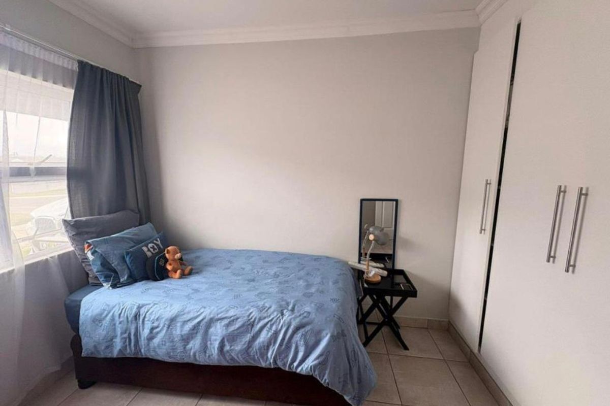A well-maintained bedroom featuring neutral walls, tiled flooring, and a spacious built-in wardrobe.