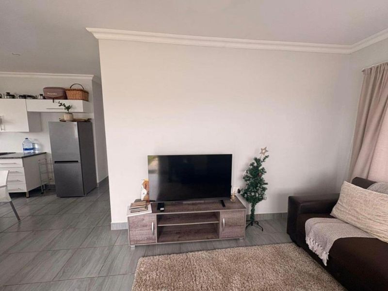 Open plan living area featuring neutral tiled flooring, crown molding, and a seamless transition into the adjacent kitchen space.