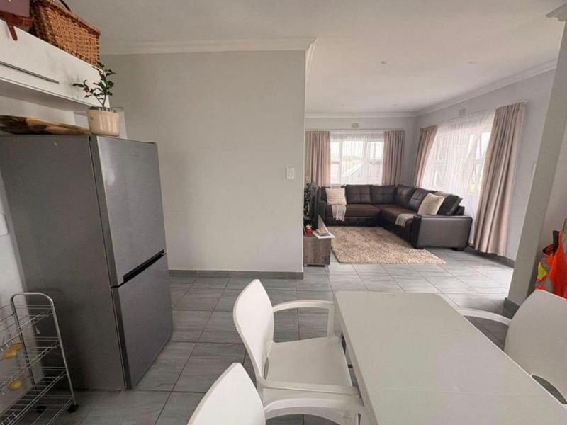 Open-plan living and dining area featuring neutral tiled flooring, recessed lighting, and a seamless flow between the kitchen and lounge space.