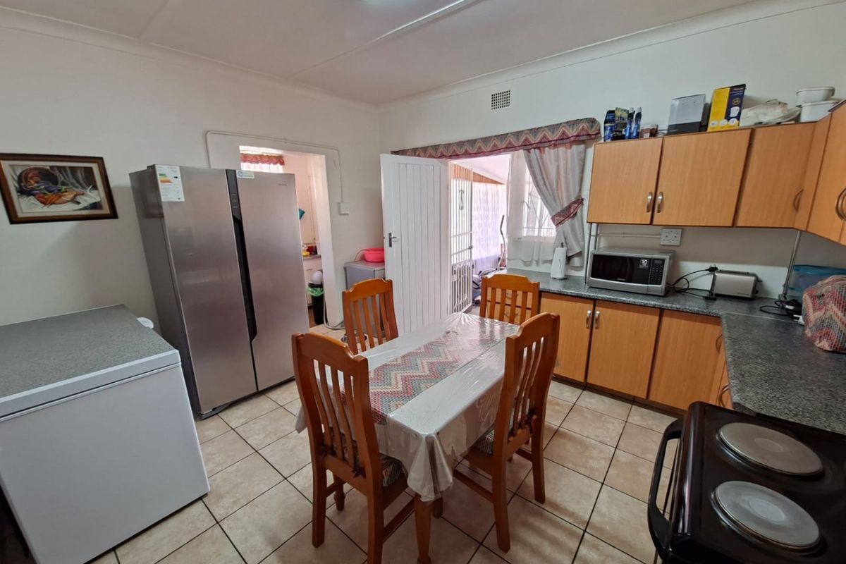 Functional kitchen featuring laminate cabinetry, tiled flooring, and direct access to an adjacent utility area.