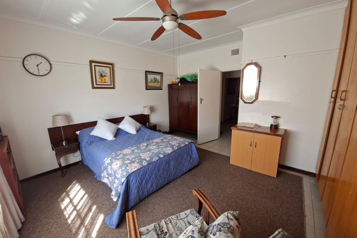 A spacious bedroom featuring a ceiling fan, built-in cupboards, and classic picture rail detailing, offering a functional layout with neutral wall finishes.