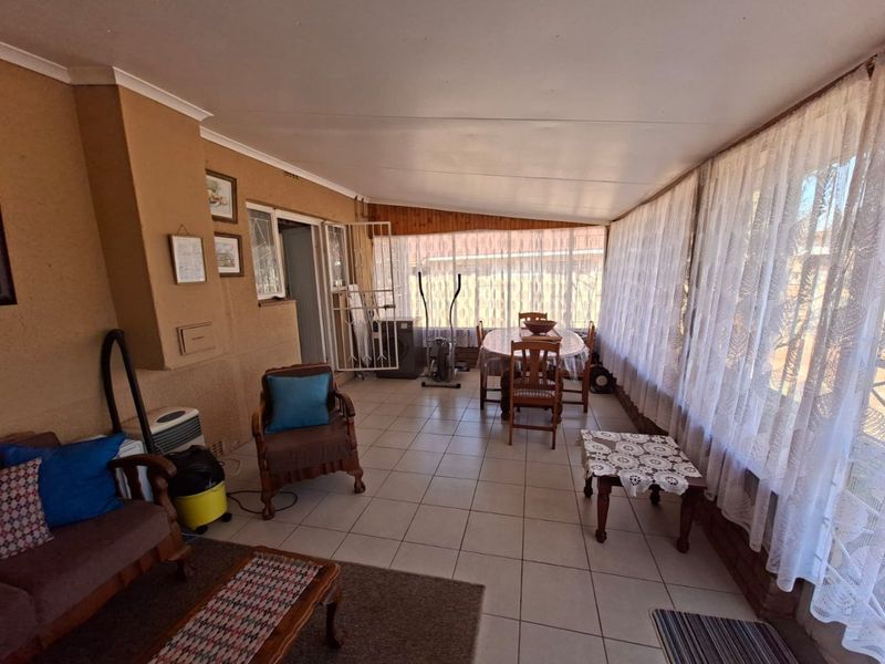 A spacious enclosed patio area featuring tiled flooring and large windows, offering a versatile space for relaxation or dining.