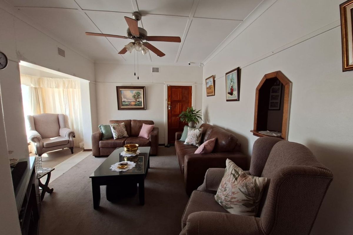 A comfortable living room featuring a ceiling fan, carpeted flooring, and a unique arched wall niche, providing a warm and inviting atmosphere.