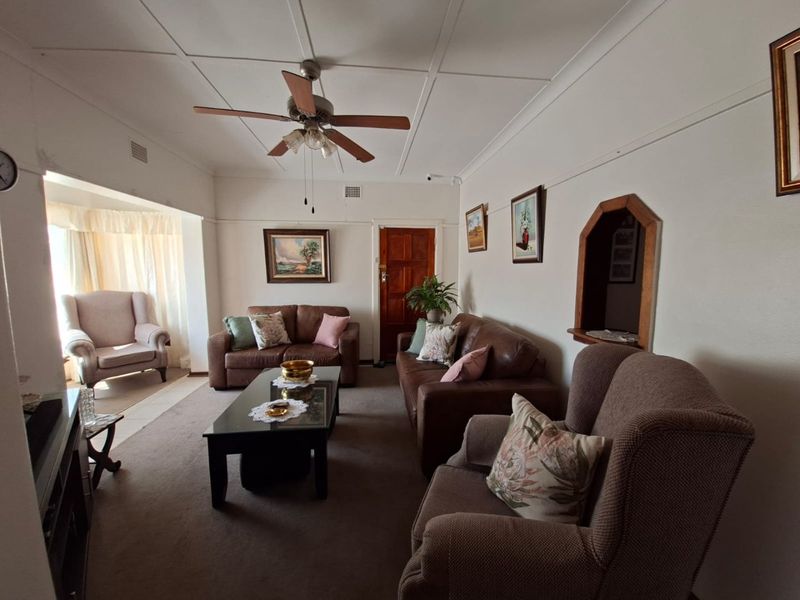 A comfortable living room featuring a ceiling fan, carpeted flooring, and a unique arched wall niche, providing a warm and inviting atmosphere.