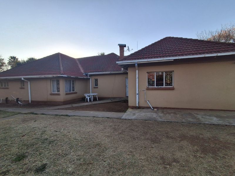 Rear view of the house featuring a tiled roof, concrete pathways, and security bars on the windows.