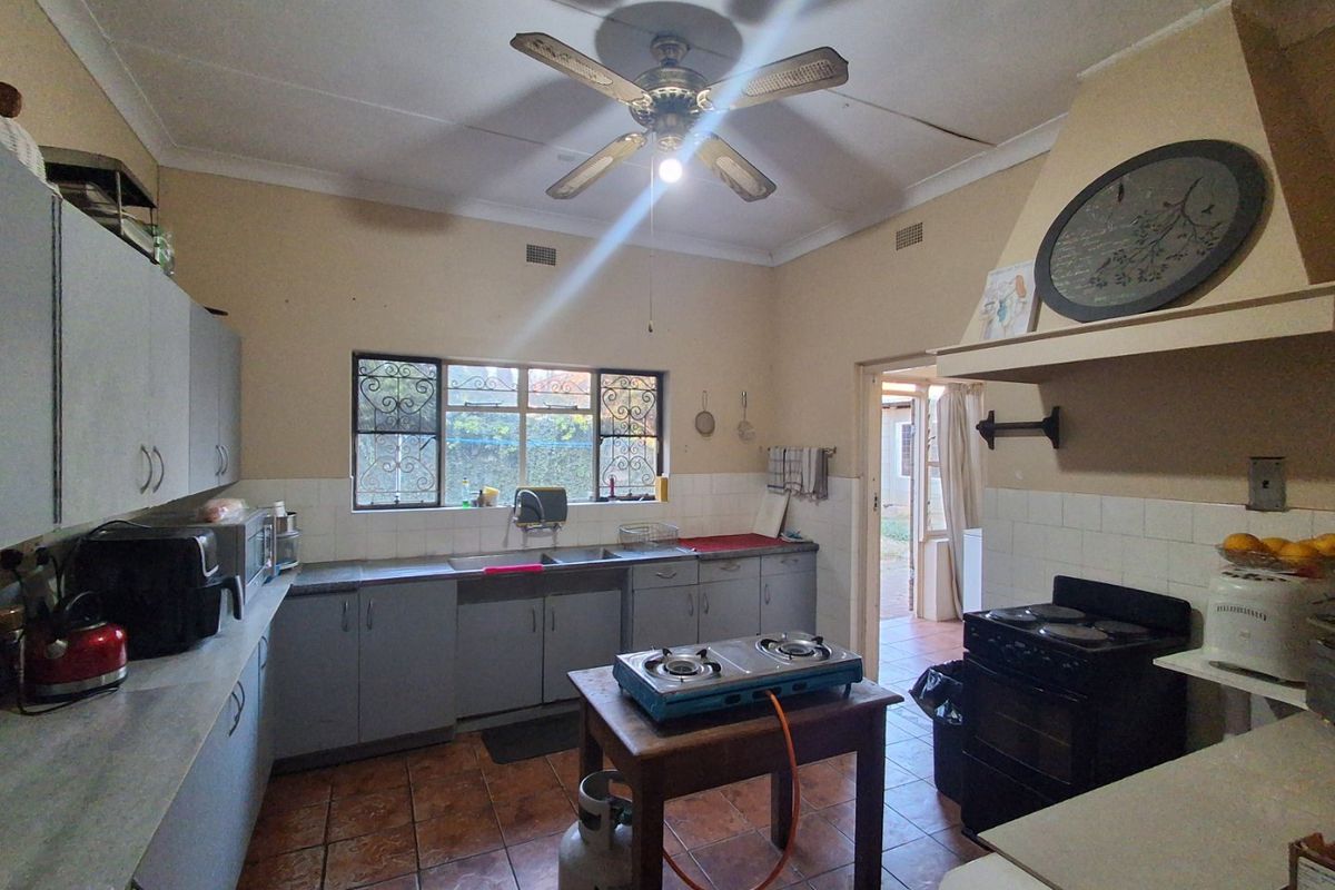 A dated kitchen featuring built-in cabinetry, tiled flooring, and a ceiling fan, offering a functional layout with potential for modern renovation.
