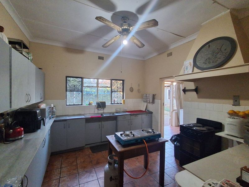 A dated kitchen featuring built-in cabinetry, tiled flooring, and a ceiling fan, offering a functional layout with potential for modern renovation.