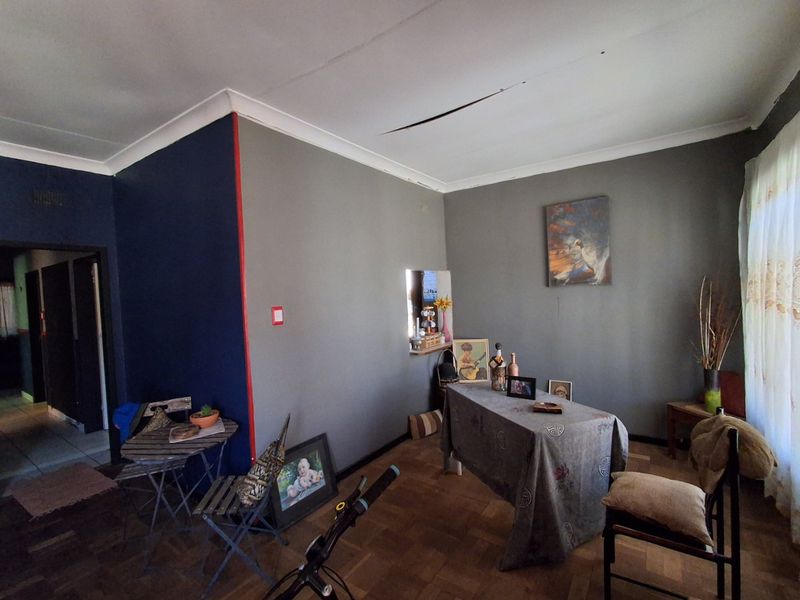A living room featuring parquet flooring and a serving hatch, currently showing signs of ceiling damage requiring repair.