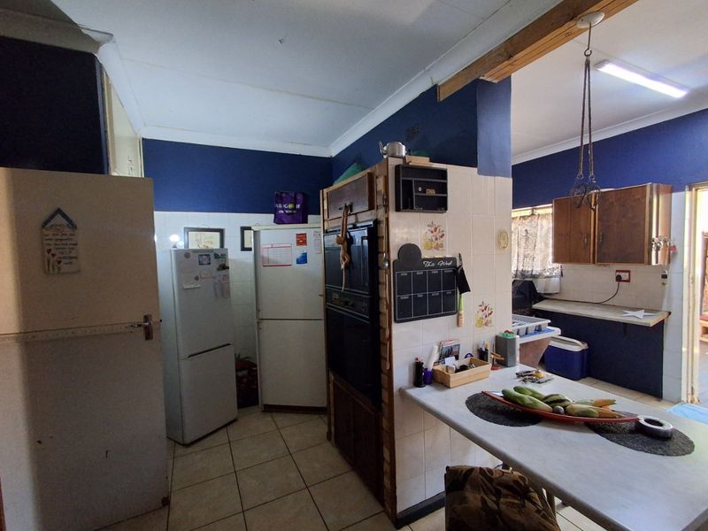 A dated kitchen featuring built-in oven, tiled flooring, and tiled splashbacks, offering potential for a modern renovation to enhance functionality and aesthetic appeal.