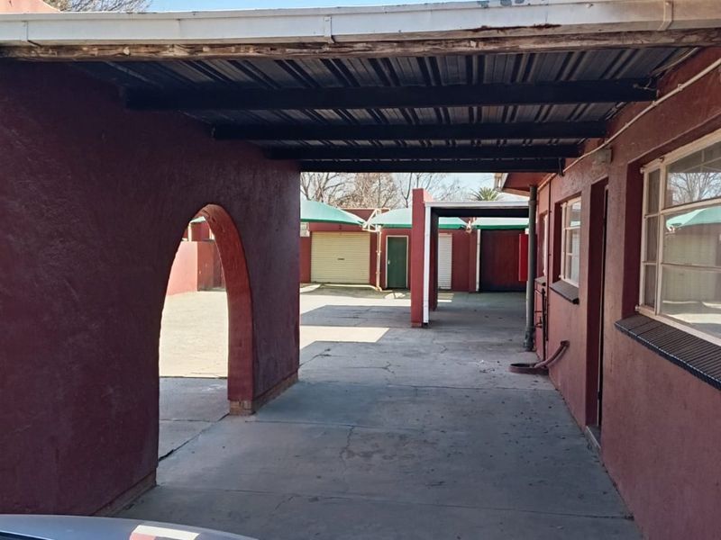 A covered carport area featuring a distinctive archway, concrete driveway, and metal roofing structure, providing sheltered parking space for the property.