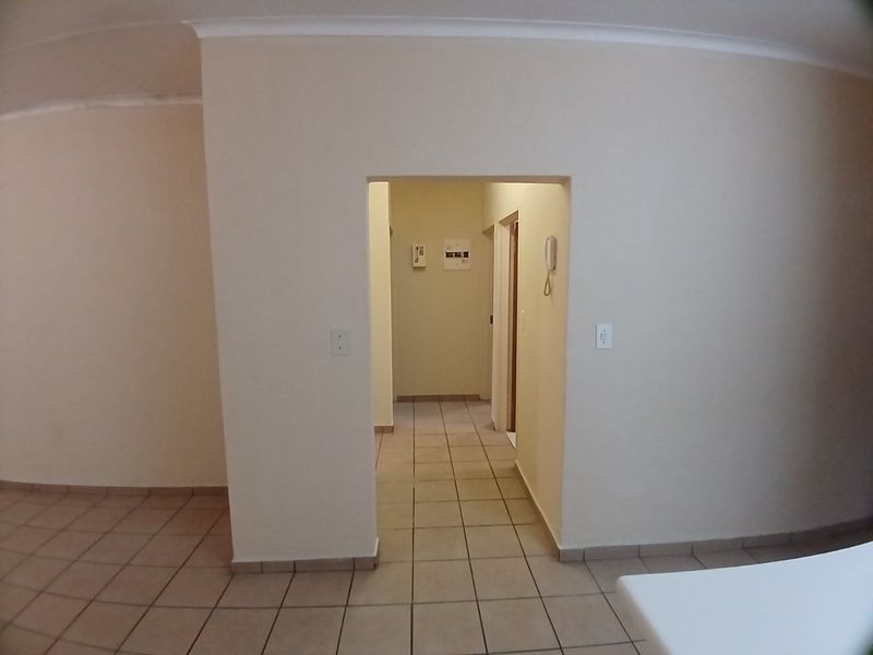 A neutral, tiled hallway area featuring an intercom system and access to adjacent rooms, presenting a clean and functional transition space.
