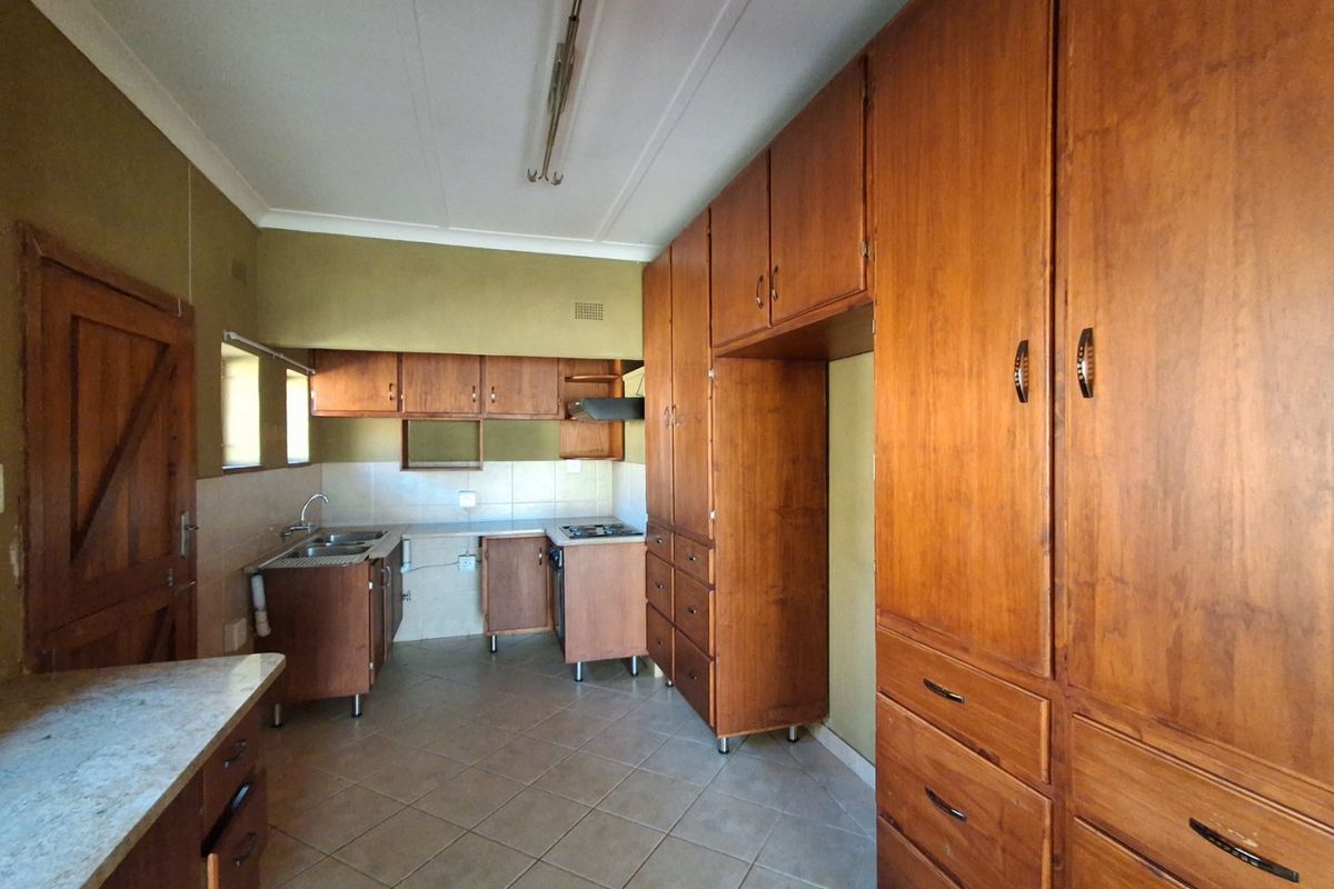 A functional kitchen featuring extensive built-in wooden cabinetry, tiled flooring, and a tiled backsplash, offering a classic layout ready for modern updates.