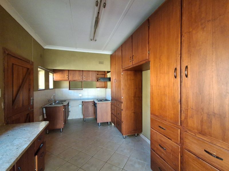 A functional kitchen featuring extensive built-in wooden cabinetry, tiled flooring, and a tiled backsplash, offering a classic layout ready for modern updates.
