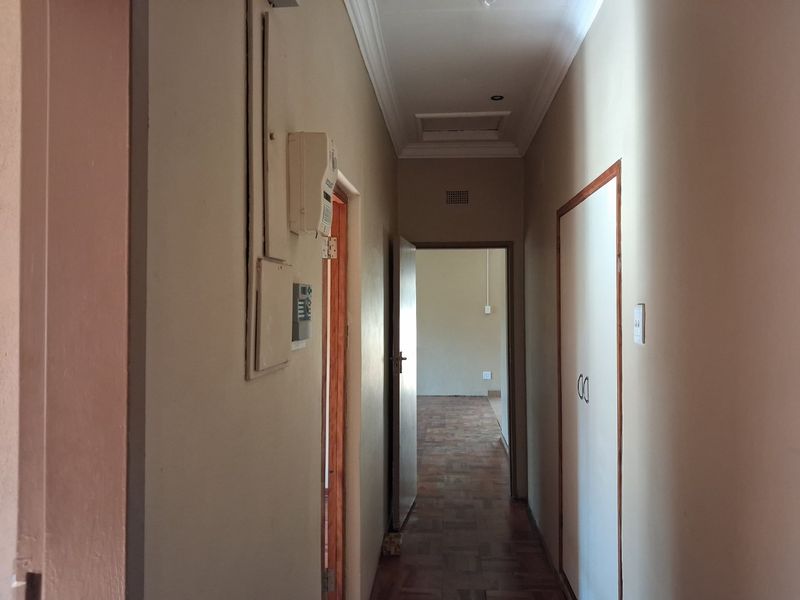 A functional hallway featuring parquet flooring, built-in storage cupboards, and access to adjacent rooms, presenting a neutral canvas for interior updates.