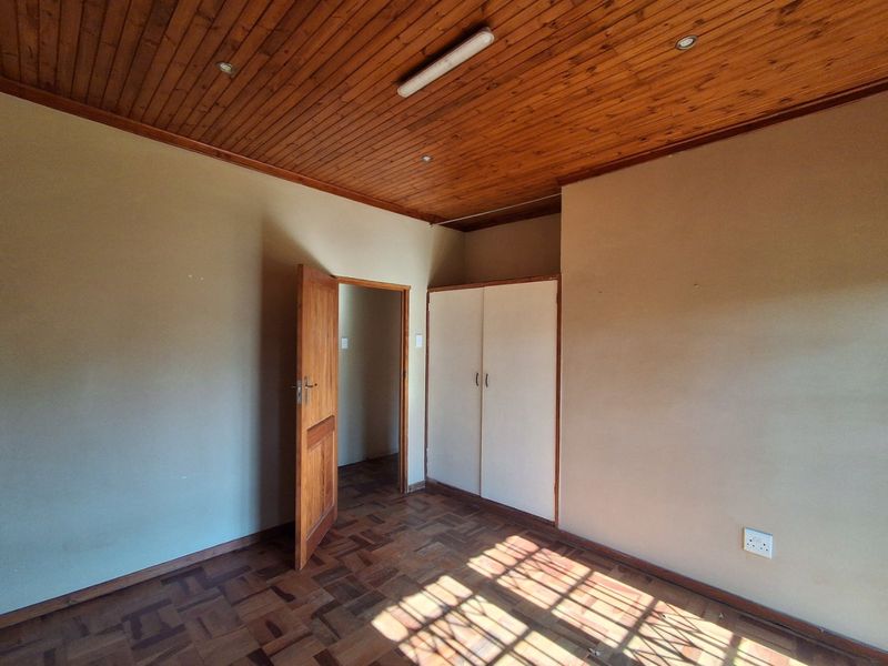 A vacant bedroom featuring classic parquet flooring, a timber-clad ceiling, and a built-in wardrobe.