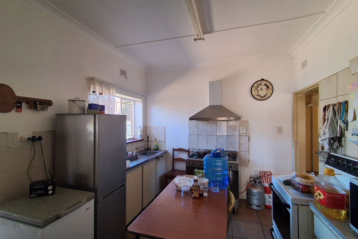 A functional kitchen featuring tiled flooring, a stainless steel extractor fan, tiled splashbacks, and built-in cabinetry with a practical layout.