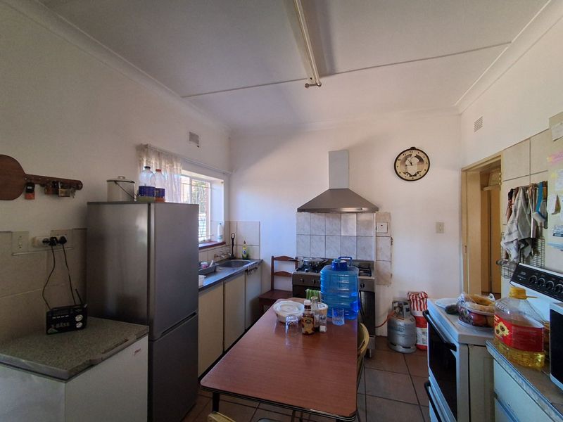 A functional kitchen featuring tiled flooring, a stainless steel extractor fan, tiled splashbacks, and built-in cabinetry with a practical layout.