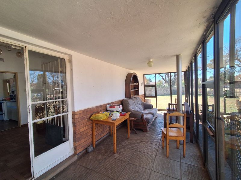 An enclosed patio area featuring tiled flooring, large aluminium windows, and direct access to the main living space through a security gate.