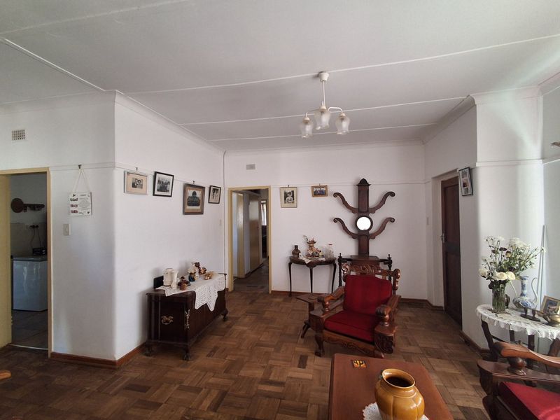 A spacious living room featuring classic parquet flooring, coved cornicing, and neutral wall finishes, offering a versatile layout for comfortable family living.