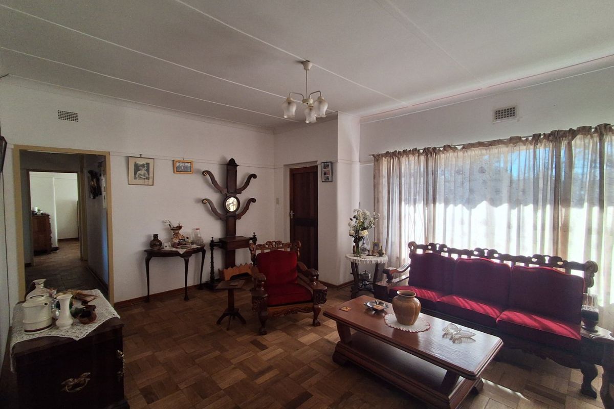 A spacious living room featuring classic parquet flooring and a traditional ceiling light fixture, offering a warm and inviting atmosphere.