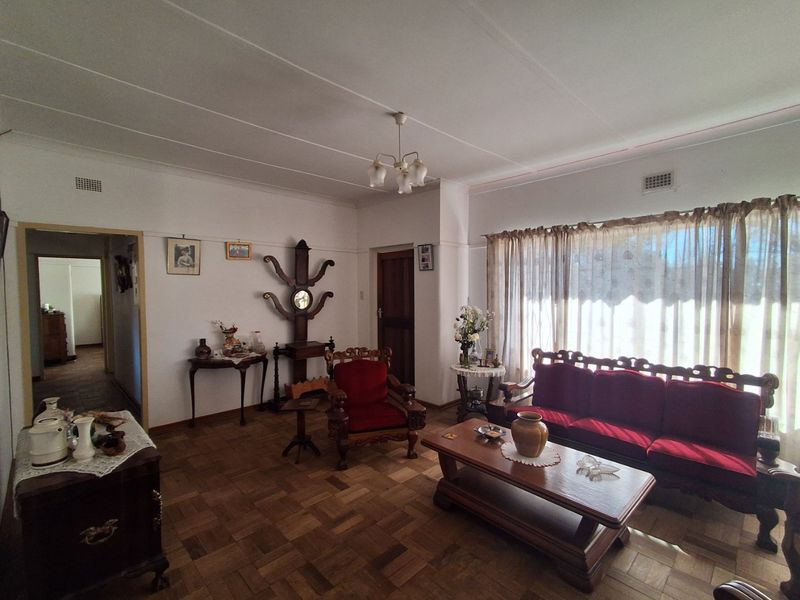 A spacious living room featuring classic parquet flooring and a traditional ceiling light fixture, offering a warm and inviting atmosphere.