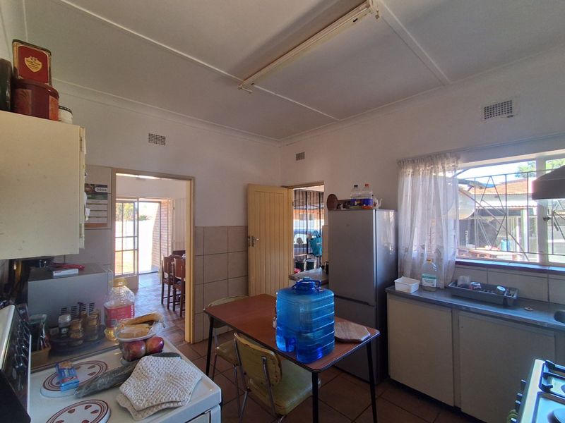 A functional kitchen featuring built-in cabinetry, tiled splashbacks, and a stainless steel sink, with direct access to adjacent living areas.