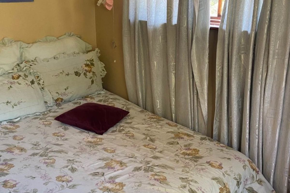 A cozy bedroom featuring laminate flooring and a window with natural light, offering a comfortable space for rest.