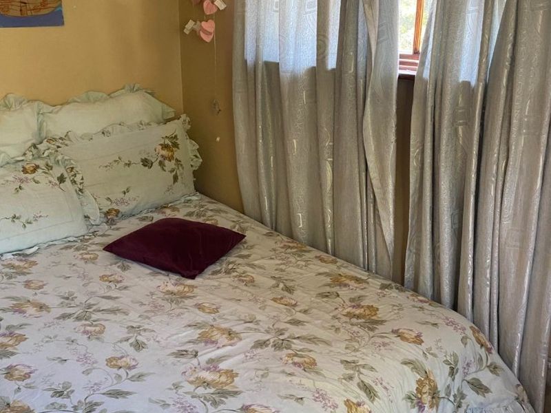 A cozy bedroom featuring laminate flooring and a window with natural light, offering a comfortable space for rest.