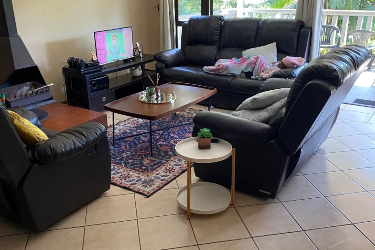 Spacious living room featuring tiled flooring, a built-in fireplace, and large sliding glass doors that provide access to an outdoor patio area.