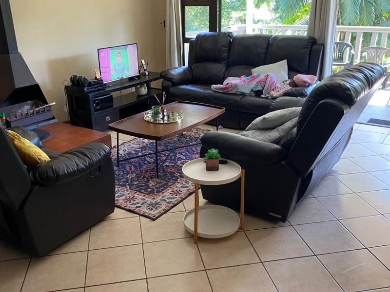 Spacious living room featuring tiled flooring, a built-in fireplace, and large sliding glass doors that provide access to an outdoor patio area.