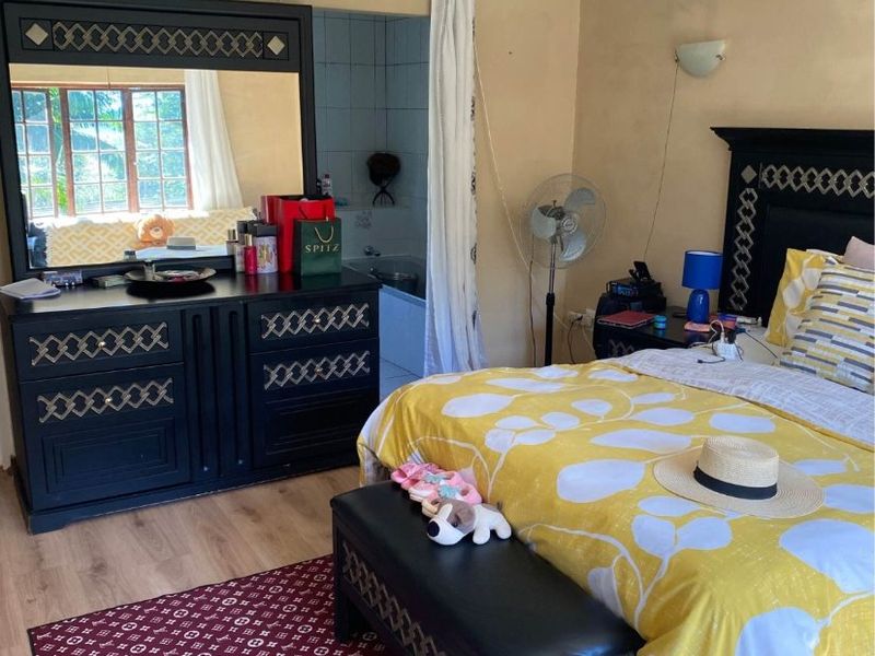 A bedroom featuring laminate flooring, a ceiling fan, and direct access to an en-suite bathroom.
