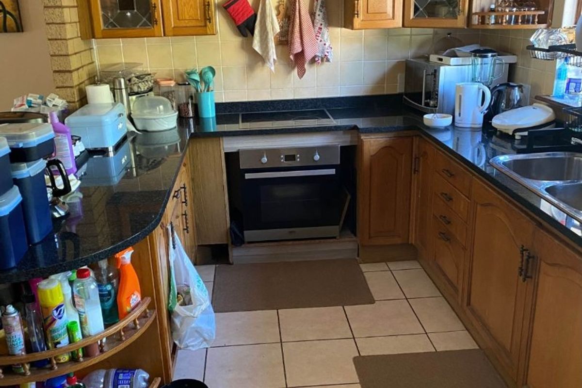 A functional kitchen featuring wooden cabinetry, granite countertops, a built-in oven, and ceramic tile flooring, offering a classic layout with ample storage space.