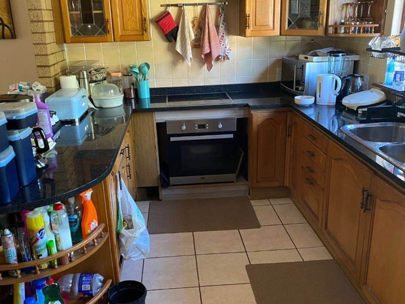 A functional kitchen featuring wooden cabinetry, granite countertops, a built-in oven, and ceramic tile flooring, offering a classic layout with ample storage space.