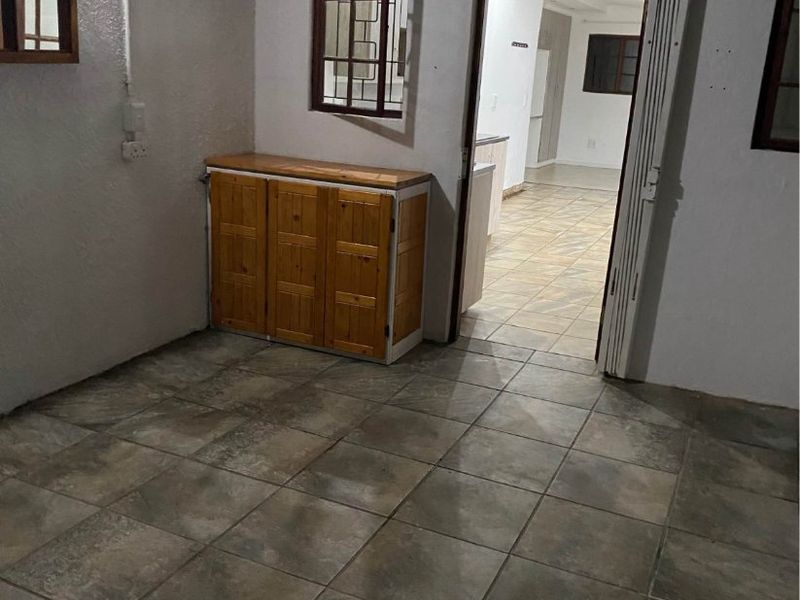 A covered patio area with tiled flooring and a security gate leading into the interior of the apartment.