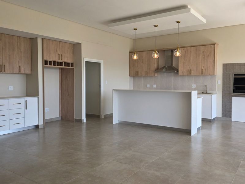 Spacious open-plan living area featuring a modern kitchen with built-in cabinetry, a central island, and an integrated indoor braai area.