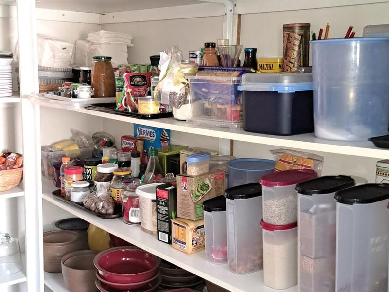 A functional pantry or scullery area featuring extensive built-in shelving for organized storage of kitchen essentials and dry goods.