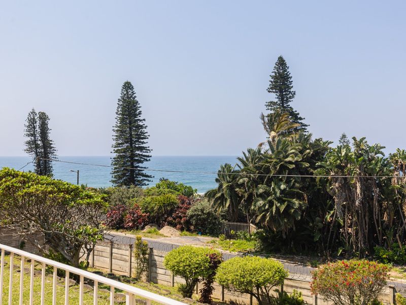 Elevated view overlooking the coastal landscape, featuring a metal balustrade in the foreground and a secure boundary wall.