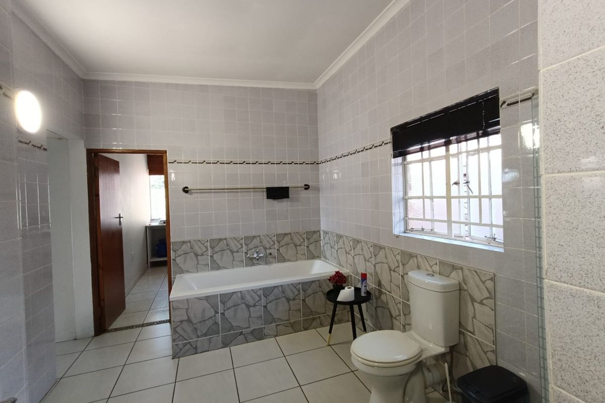 A functional bathroom featuring a built-in bathtub, ceramic tiling, and a standard toilet, offering a clean and practical layout.